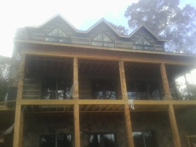 Dormers and porch framing on a large log home under construction — Roof Coating work by our crew in Henrietta